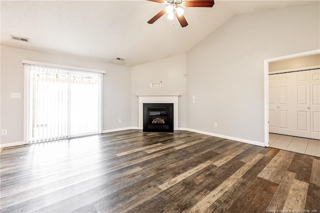 unfurnished living room featuring a glass covered fireplace, visible vents, vaulted ceiling, and wood finished floors