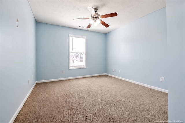 carpeted empty room with ceiling fan, visible vents, and baseboards