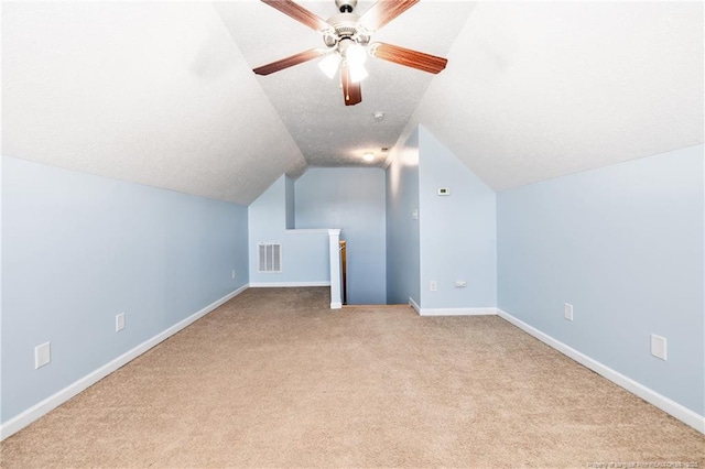 additional living space with baseboards, visible vents, vaulted ceiling, a textured ceiling, and carpet flooring