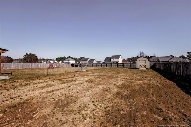 view of yard with a storage shed, a fenced backyard, a playground, and an outdoor structure