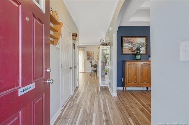 foyer featuring light wood-style floors, baseboards, and crown molding