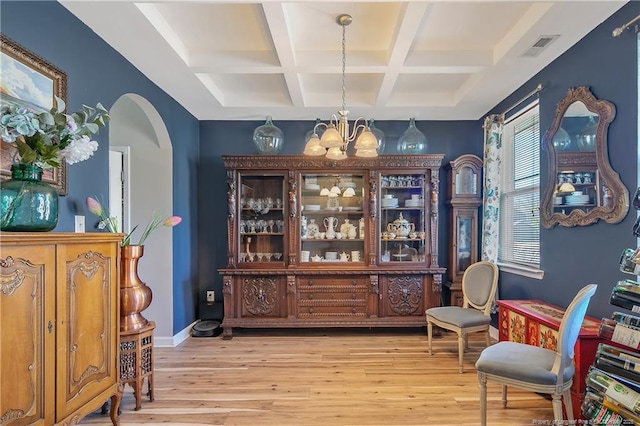 bar featuring a chandelier, arched walkways, baseboards, and light wood finished floors