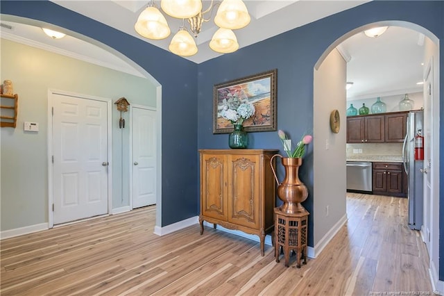 interior space with light wood-style floors, crown molding, and baseboards