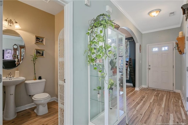 interior space featuring light wood-style floors, baseboards, visible vents, and ornamental molding