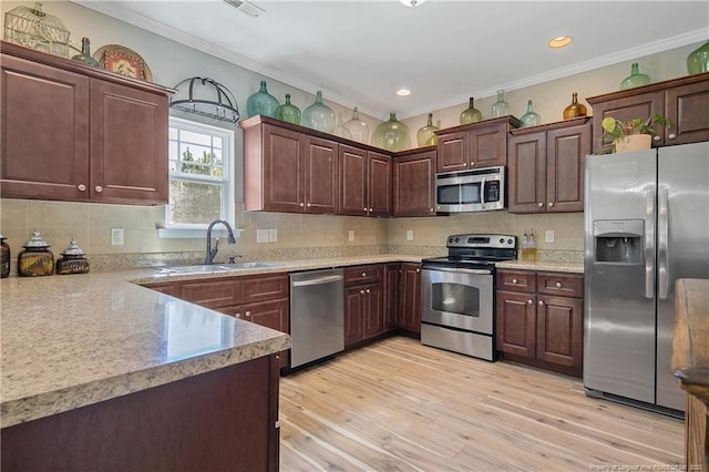 kitchen featuring crown molding, stainless steel appliances, a sink, and light wood-style floors