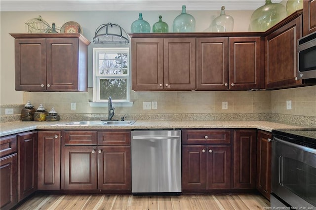 kitchen with light wood-style floors, tasteful backsplash, appliances with stainless steel finishes, and a sink