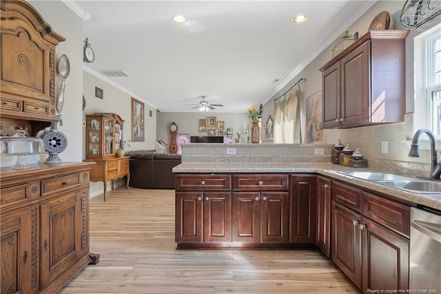 kitchen with crown molding, stainless steel dishwasher, light wood-style floors, a sink, and a peninsula