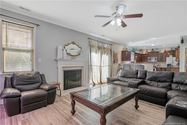 living room featuring light wood finished floors, plenty of natural light, visible vents, and ornamental molding