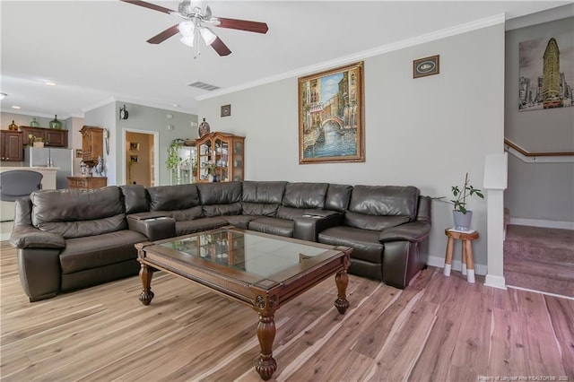 living room with baseboards, light wood-style flooring, visible vents, and crown molding