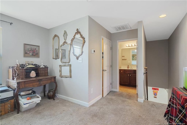 hall with light colored carpet, visible vents, a sink, and baseboards