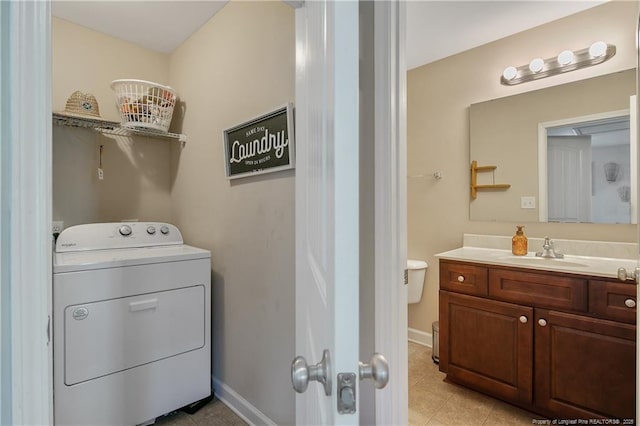 laundry area featuring light tile patterned floors, a sink, washer / dryer, laundry area, and baseboards