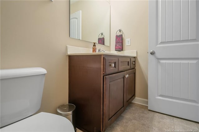 half bathroom featuring toilet, tile patterned flooring, and vanity