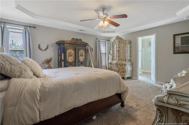 carpeted bedroom with visible vents, baseboards, a raised ceiling, and a ceiling fan