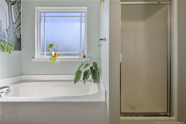 bathroom with a healthy amount of sunlight, a stall shower, and a bath