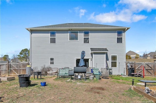 rear view of property featuring a vegetable garden, a gate, and fence