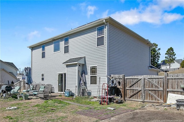 back of house featuring a patio, fence, and a gate