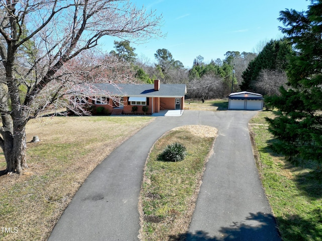 view of front facade featuring a garage, an outdoor structure, a chimney, and a front lawn