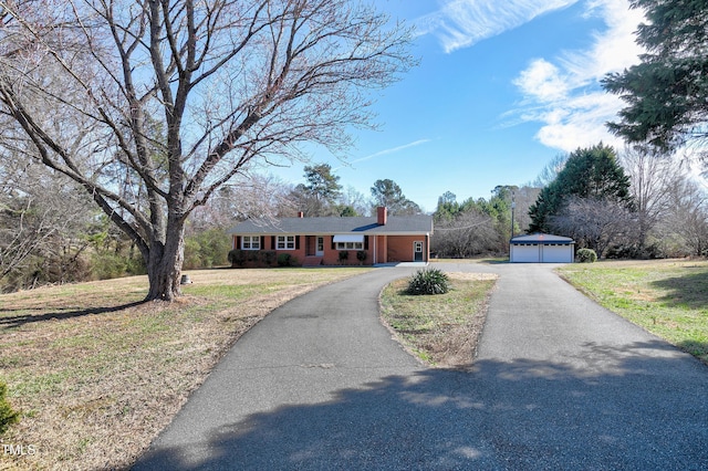 ranch-style home featuring a front yard, an outdoor structure, a chimney, and a detached garage