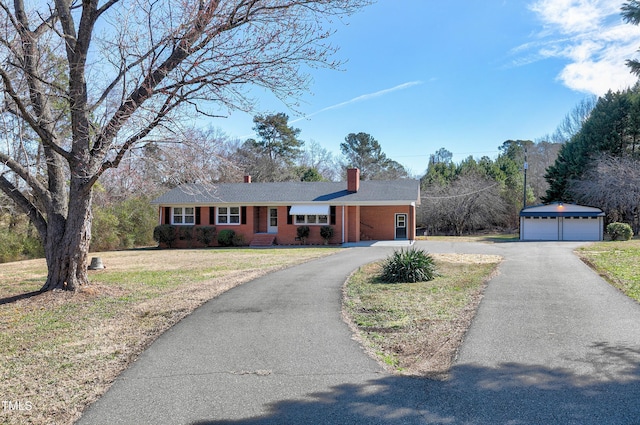 single story home with an outbuilding, brick siding, a detached garage, a front lawn, and a chimney