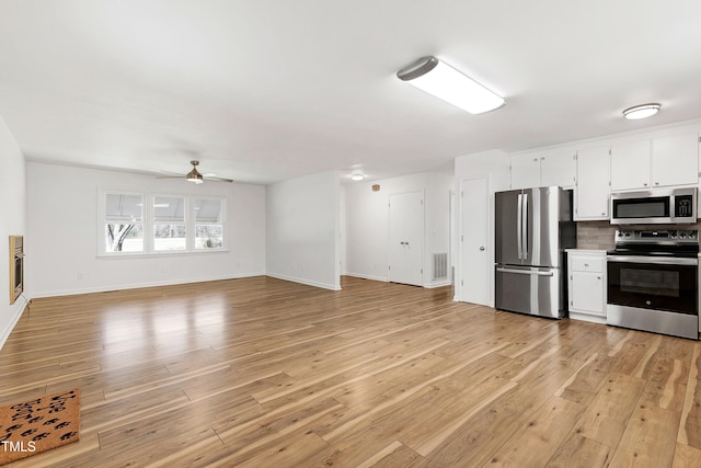 kitchen with visible vents, white cabinets, appliances with stainless steel finishes, light wood-type flooring, and decorative backsplash