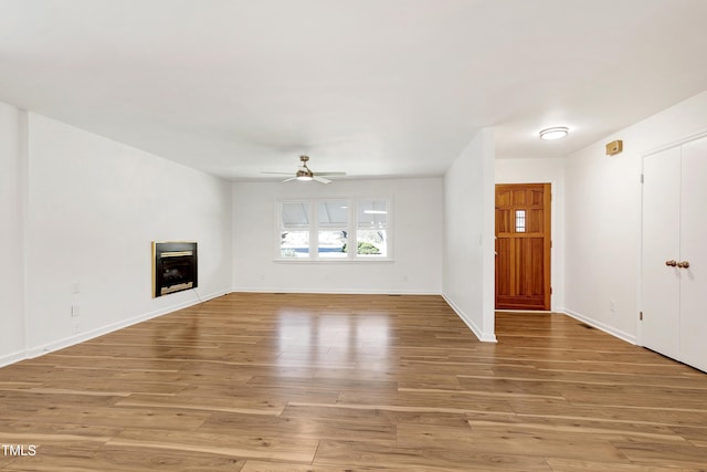 unfurnished living room with a ceiling fan, baseboards, a fireplace, and light wood finished floors