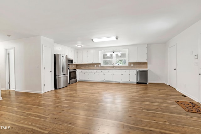 kitchen featuring decorative backsplash, wood finished floors, light countertops, stainless steel appliances, and a sink