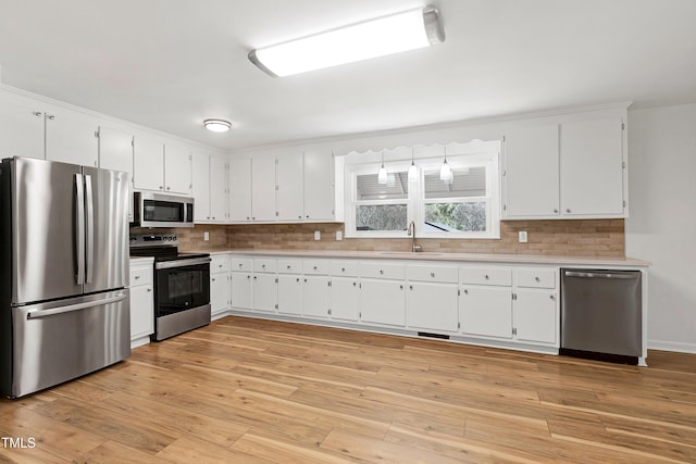 kitchen with decorative backsplash, appliances with stainless steel finishes, light countertops, and a sink