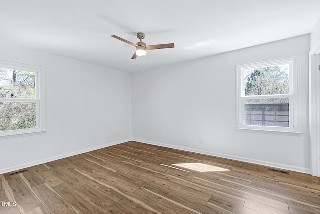 empty room featuring wood finished floors, visible vents, and baseboards