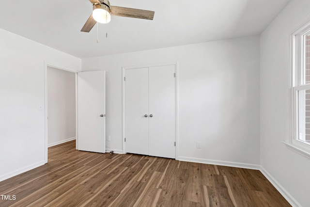 unfurnished bedroom with multiple windows, wood finished floors, and baseboards