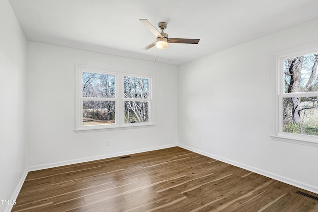 unfurnished room with a healthy amount of sunlight, baseboards, and dark wood finished floors