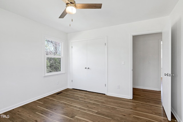 unfurnished bedroom with a closet, wood finished floors, visible vents, and baseboards