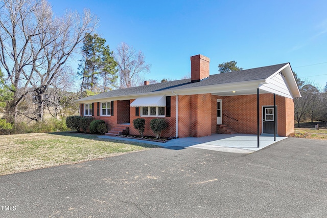 ranch-style home with a carport, entry steps, brick siding, and a chimney