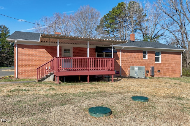 back of property with brick siding, a chimney, cooling unit, and a lawn