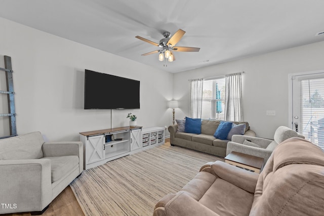 living room with visible vents, light wood-style floors, a ceiling fan, and a healthy amount of sunlight