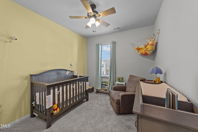 bedroom with ceiling fan, visible vents, baseboards, a nursery area, and carpet