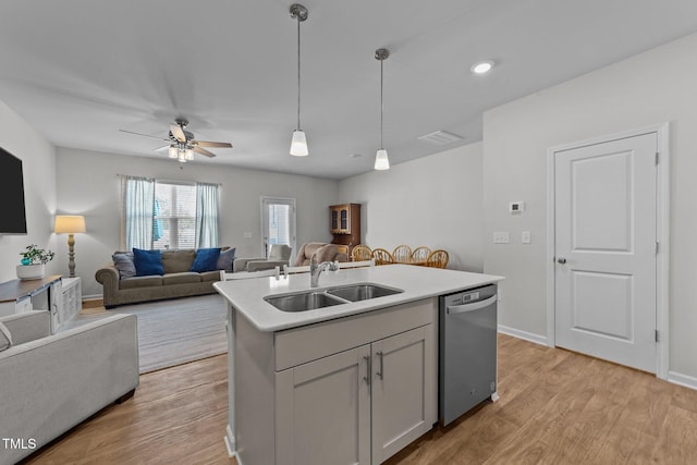 kitchen featuring a sink, light wood finished floors, stainless steel dishwasher, and hanging light fixtures