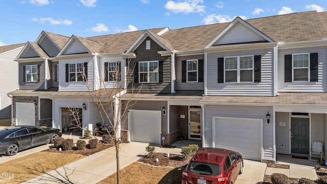 view of property featuring a garage, concrete driveway, brick siding, and roof with shingles