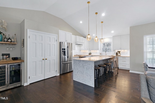 kitchen featuring dark wood-style floors, a kitchen island, stainless steel appliances, wine cooler, and white cabinets