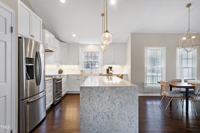 kitchen with custom range hood, light stone counters, dark wood-style floors, and appliances with stainless steel finishes