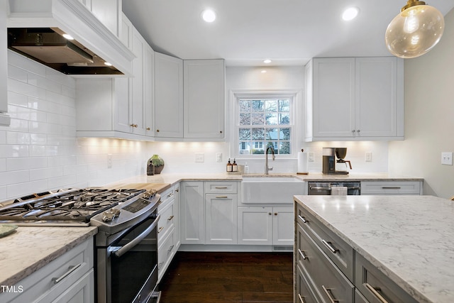 kitchen with a sink, stainless steel gas stove, light stone counters, and custom range hood