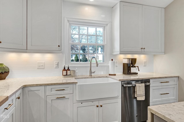 kitchen featuring light stone countertops, dishwasher, decorative backsplash, white cabinets, and a sink