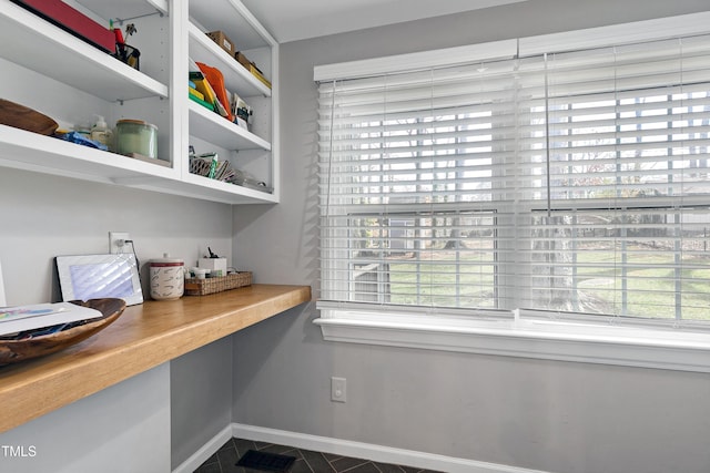 office space with visible vents, baseboards, and built in desk