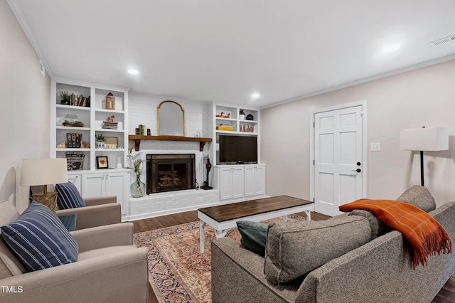 living room featuring a brick fireplace, wood finished floors, visible vents, and ornamental molding