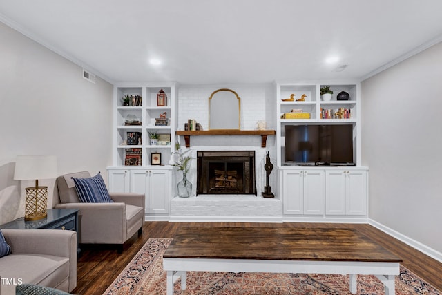 living area featuring visible vents, built in shelves, crown molding, dark wood-type flooring, and a fireplace