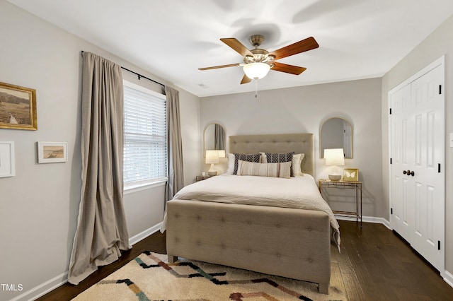 bedroom featuring a closet, baseboards, ceiling fan, and dark wood-style flooring