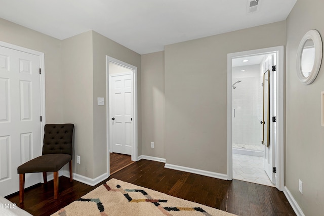 bedroom with dark wood finished floors, visible vents, ensuite bathroom, and baseboards