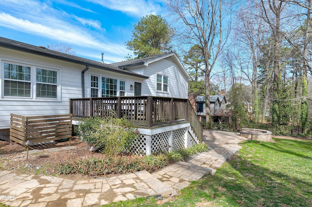 rear view of property with a yard, a fire pit, and a wooden deck