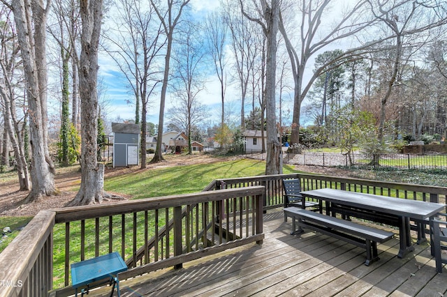 wooden deck featuring an outdoor structure, a storage unit, a lawn, and fence