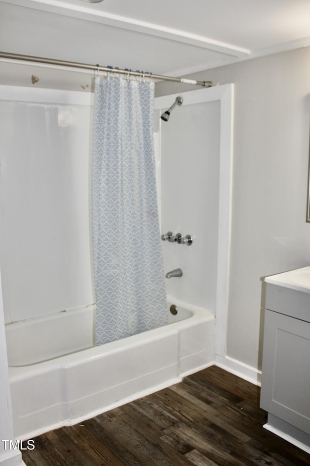 bathroom featuring shower / tub combo, vanity, baseboards, and wood finished floors