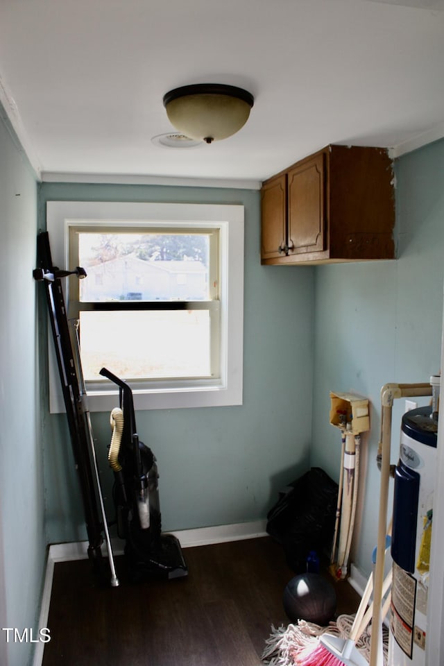 workout area featuring water heater, baseboards, and dark wood finished floors